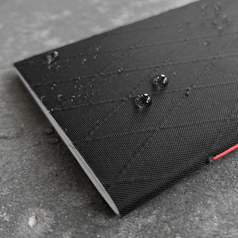 Black Diamond Tactical Pockit notebook with water droplets on a concrete surface